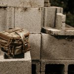 Pouch sits on cinder blocks outside with plants.