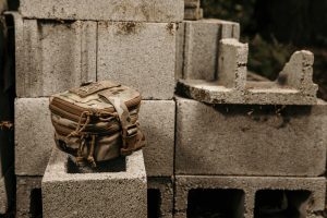 Pouch sits on cinder blocks outside with plants.