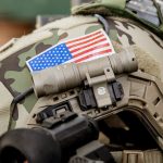 Camouflage helmet, US flag, Surefire helmet light attached.