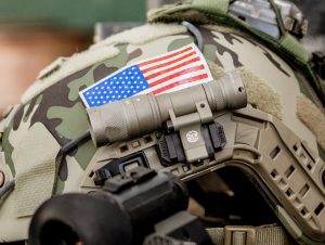 Camouflage helmet, US flag, Surefire helmet light attached.